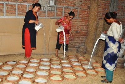 भक्तपुरको लिवालीस्थित सैंजु दही भण्डारमा जु जु धौ बनाउँदै महिलाहरु । 